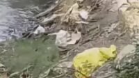 Warga menutupi orok bayi dengan mantel hujan warna kuning usai ditemukan di aliran sungai