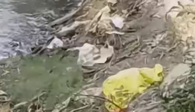 Warga menutupi orok bayi dengan mantel hujan warna kuning usai ditemukan di aliran sungai